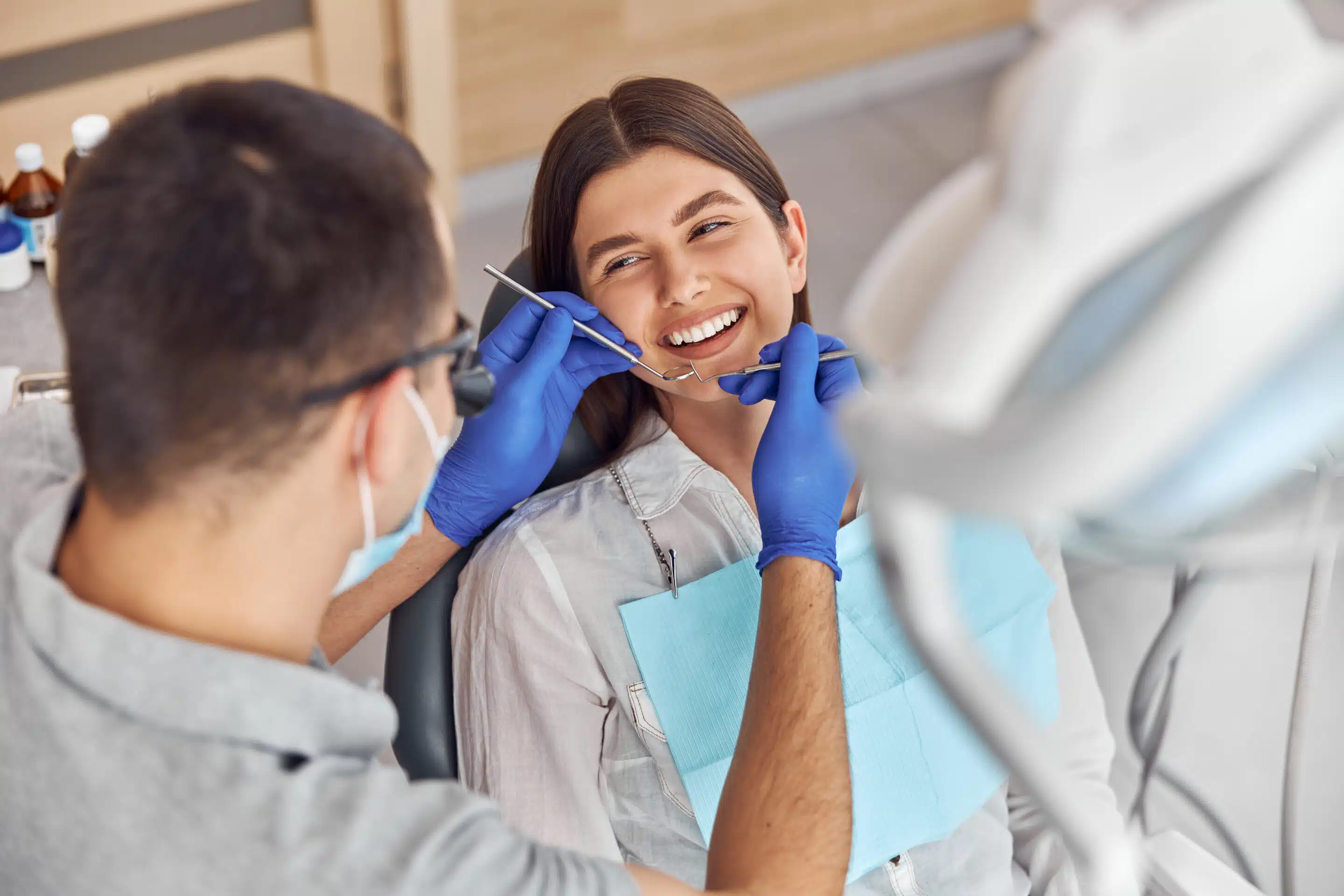 Cheerful positive dentist and client in dentistry. They look at each other and smile. Female client sit in chair